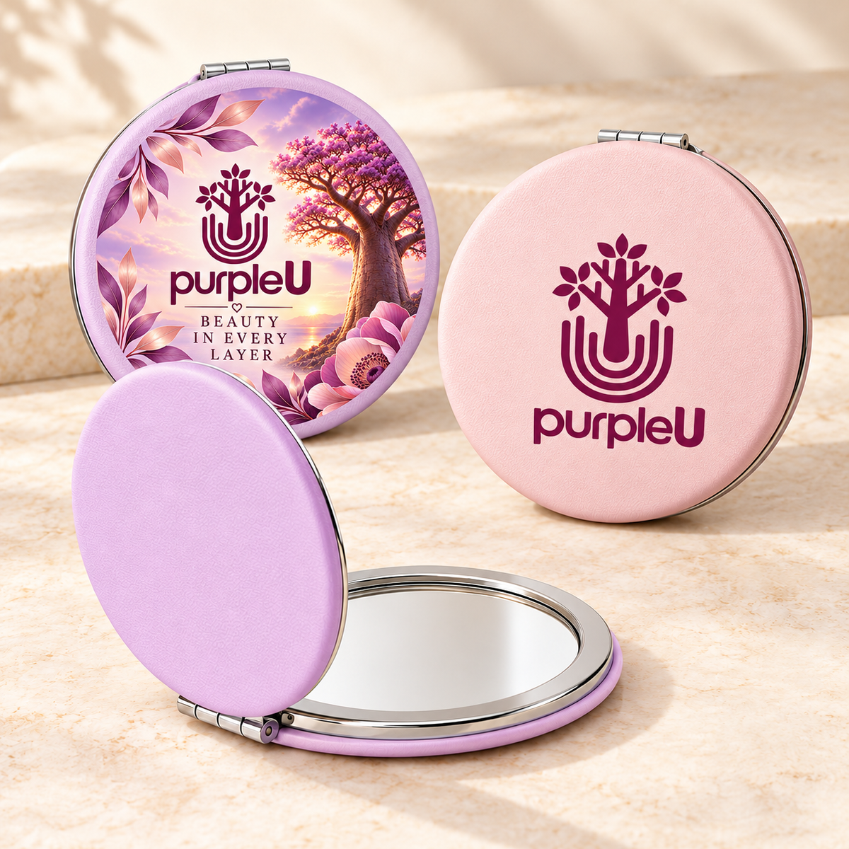 Lavender compact mirror with Beauty in Every Layer artwork and purpleU branding, beside a blush-pink compact with purpleU emblem and wordmark and an open lavender mirror.